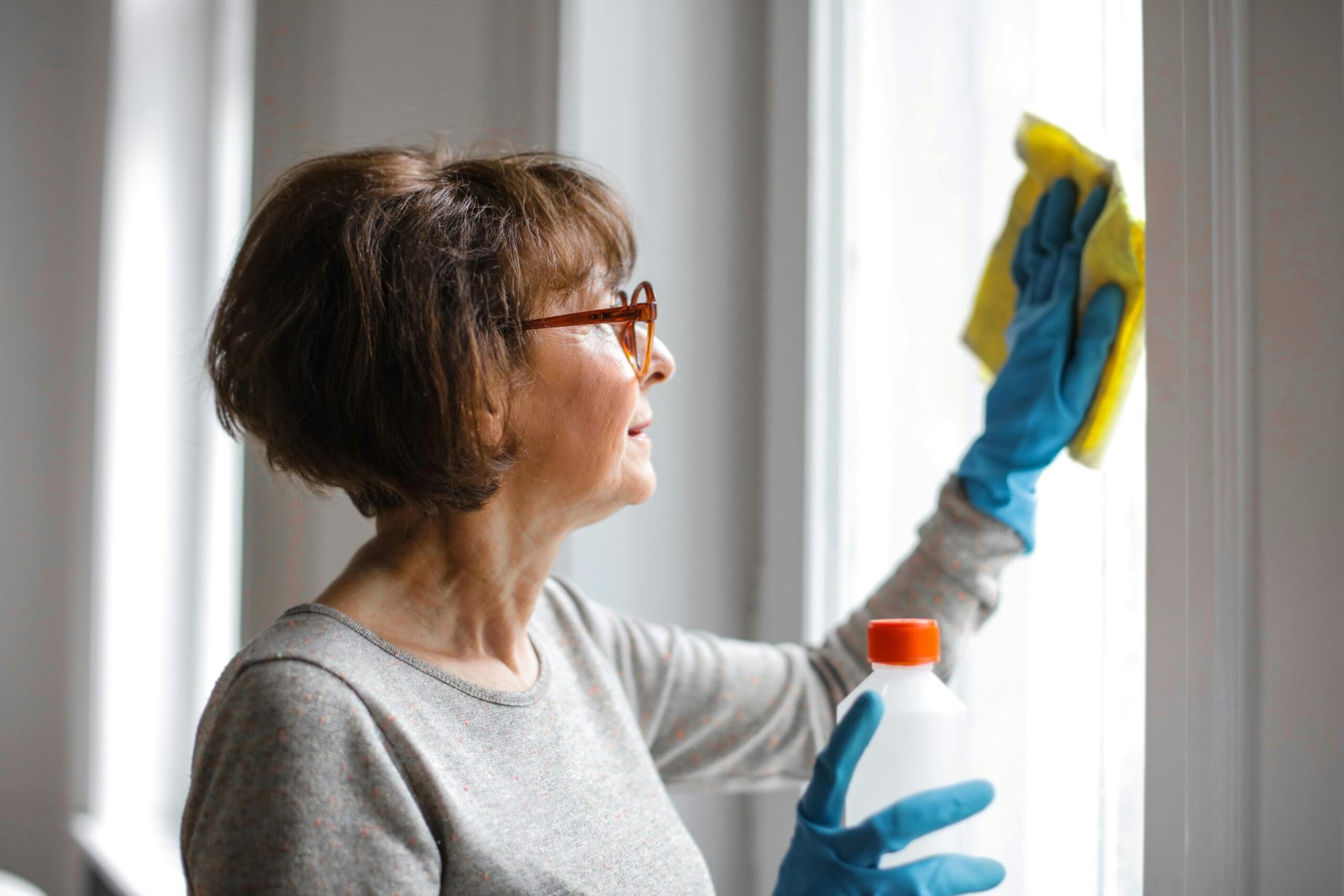 Mujer limpiando un cristal de ventana, ejemplo de limpieza de zonas olvidadas del hogar